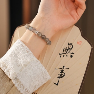 Detail of natural labradorite beaded bracelet worn on wrist with lace sleeves and fan