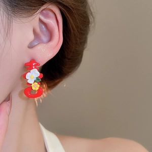 Detailed close-up of a red Xi character earring with small floral accents on a model