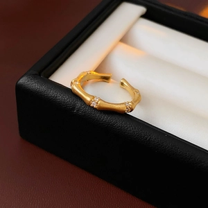 Macro detail of bamboo-style gold ring with zircon inlays in a jewelry display box