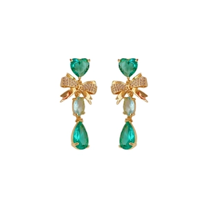 Golden bow earrings with green heart and teardrop crystals on white background