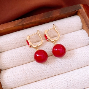 Detailed view of red pearl drop earrings with 18K gold plating and gemstone accents