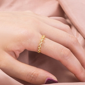 Close-up of elegant gold wave ring with micro-set zircons worn on model's hand