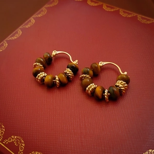 Close-up detail of vintage gold-plated hoop earrings with tiger eye stone beads