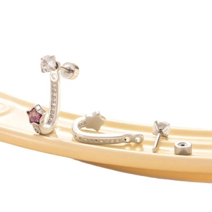 Silver star earrings set with pink opal and diamonds on a light yellow curved display