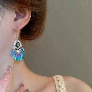 Detailed macro view of bohemian tassel earrings with blue beaded fringe on a model