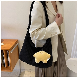 Detail of black woven shoulder tote bag featuring a cute yellow plush star charm accessory