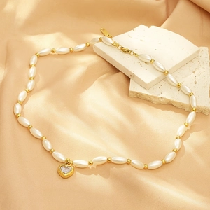 Detail of heart-shaped crystal pendant on pearl necklace with golden clasp detail