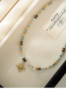 Macro shot of colorful tiger eye beaded necklace with gold star pendant on fabric