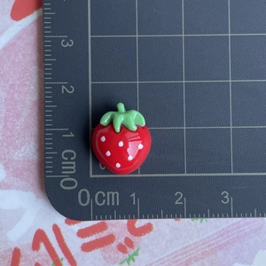 Macro shot of 1.5cm red resin strawberry charm with green leaves and white spots