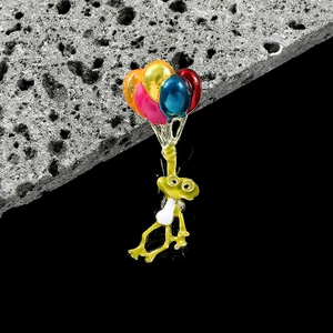 Détail macro d'une broche grenouille émaillée avec ballons colorés sur pierre