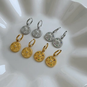Gold and silver sunburst compass earrings with colorful cubic zirconia on white tray