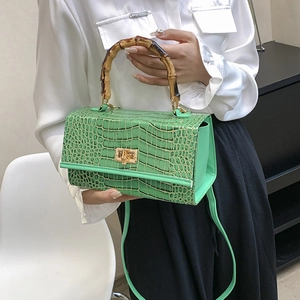 Detail showing the green crocodile pattern texture and natural bamboo handle with gold lock