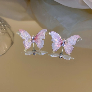 Vue macro de boucles d'oreilles papillon roses serties de diamants sur fond miroir