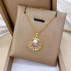 Detail of a shell-shaped gold pendant with rectangle crystals and a white center pearl