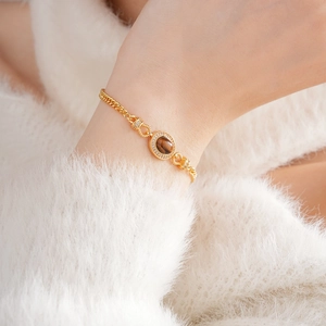 Detail of gold-plated bracelet with oval tiger eye stone and crystals on wrist