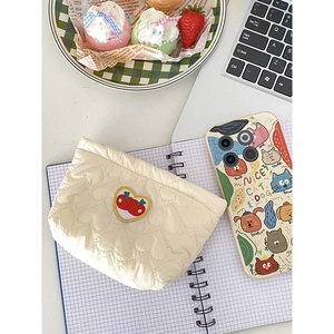 Borsa trapuntata color crema con ricamo a ciliegia cuore su una scrivania in stile lifestyle