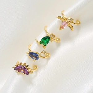 Set of four 18K gold dinosaur ear cuffs with colorful zircon stones on white silk