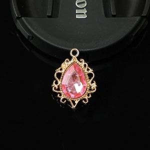 Détail d'un pendentif goutte rose serti dans un cadre doré vintage en filigrane
