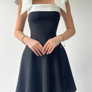 Detail of elegant black and white dress featuring a large white bow shoulder strap