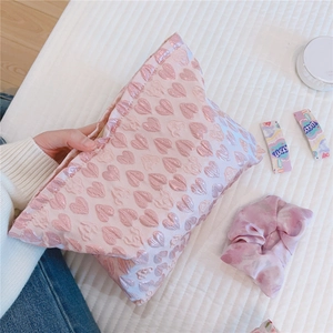 Detail showing soft pink jacquard fabric texture with embossed heart patterns on the bag