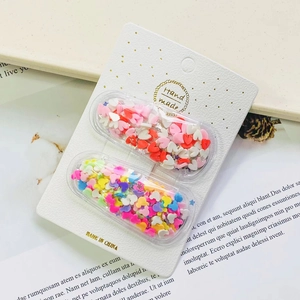 Close-up of heart and colorful sequins inside capsule-style hair clips on a card
