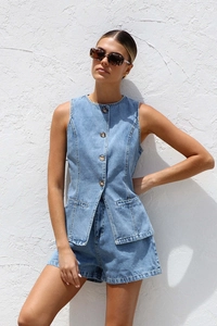 Détail d'un ensemble en jean bleu avec gilet sans manches boutonné et short assorti chic