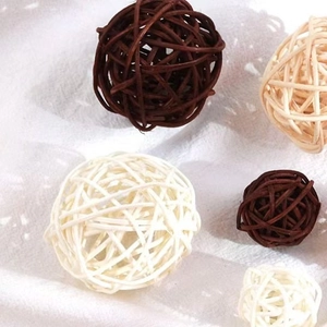 Flat lay of handmade rattan balls in brown and cream on a white fabric background
