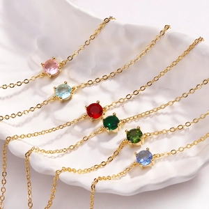 Minimalist gold chain bracelet with colorful round zircon stones on a shell plate