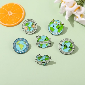 Set of 6 eco-friendly Earth Day enamel pins with Save the Planet slogans on green desk
