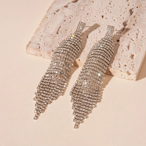Détail des boucles d'oreilles pendantes argentées avec pompons de strass scintillants