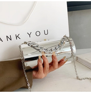 Detail of silver mirror acrylic cylindrical evening bag with thick chain handle