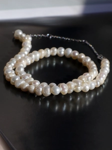 Macro shot of elegant baroque freshwater pearl necklace with silver clasp on black background