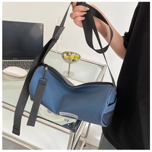 Vue détaillée du sac cylindre en nylon bleu marine avec bandoulière et poche filet