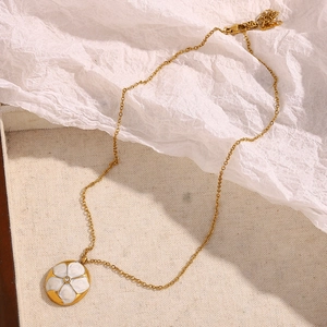 Macro detail of 18K gold-plated necklace with white enamel flower pendant and central diamond