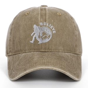 Close-up of white BELIEVE embroidery and Bigfoot silhouette on washed khaki baseball cap