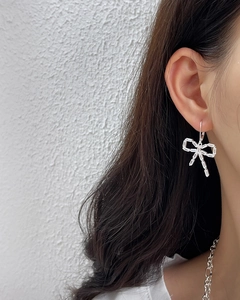 Close-up of 925 silver bow earrings with sparkling baguette zircon stones on model