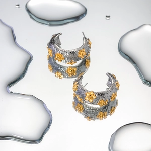 Detailed close-up of 18k gold-plated hammered flower earrings with water drop reflections