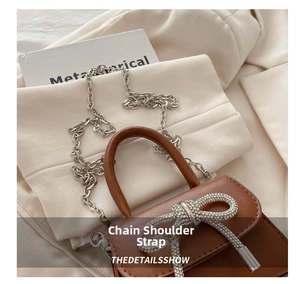 Detail shot of a brown patent leather bag featuring a luxury rhinestone bow and silver chain