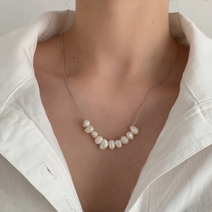 Close-up of elegant smile-shaped freshwater pearl necklace on model's neck