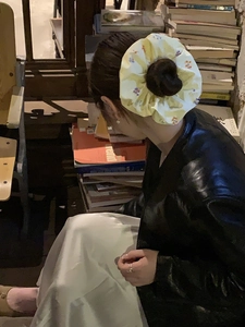 Dettaglio ravvicinato di un elastico giallo ricamato a fiori indossato su uno chignon