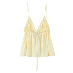 Detail showing the deep V-neck and ruffled hem of a light yellow drape camisole top