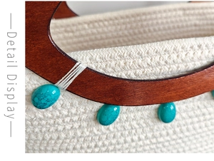 Detail of woven cotton tote bag featuring dark wood handles and turquoise stone accents