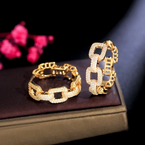 Macro shot of gold-plated chain-link hoop earrings encrusted with white cubic zirconia