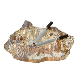 Minimalist mountain-shaped glass ashtray in amber gold finish on white background