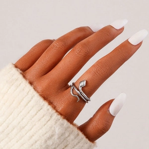 Detail view of a silver snake-shaped open ring with scales texture on a model's hand