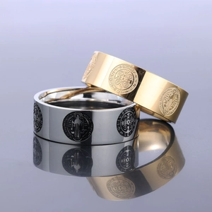 Detail of gold and silver stainless steel rings with Saint Benedict Medal engravings