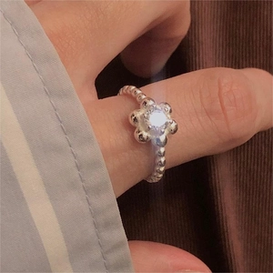 Macro shot of 925 silver flower ring with zircon stone and beaded band on finger