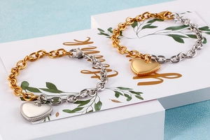 Close-up of heart pendants on two-tone gold and silver stainless steel chain bracelets