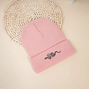 Close-up of pink knitted beanie featuring detailed black snake embroidery on the cuff