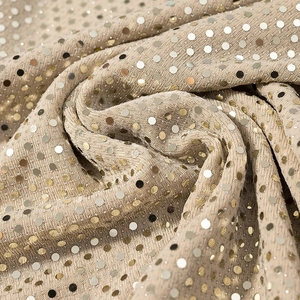 Vue détaillée des paillettes dorées au fini luxueux sur le tissu drapé élégant